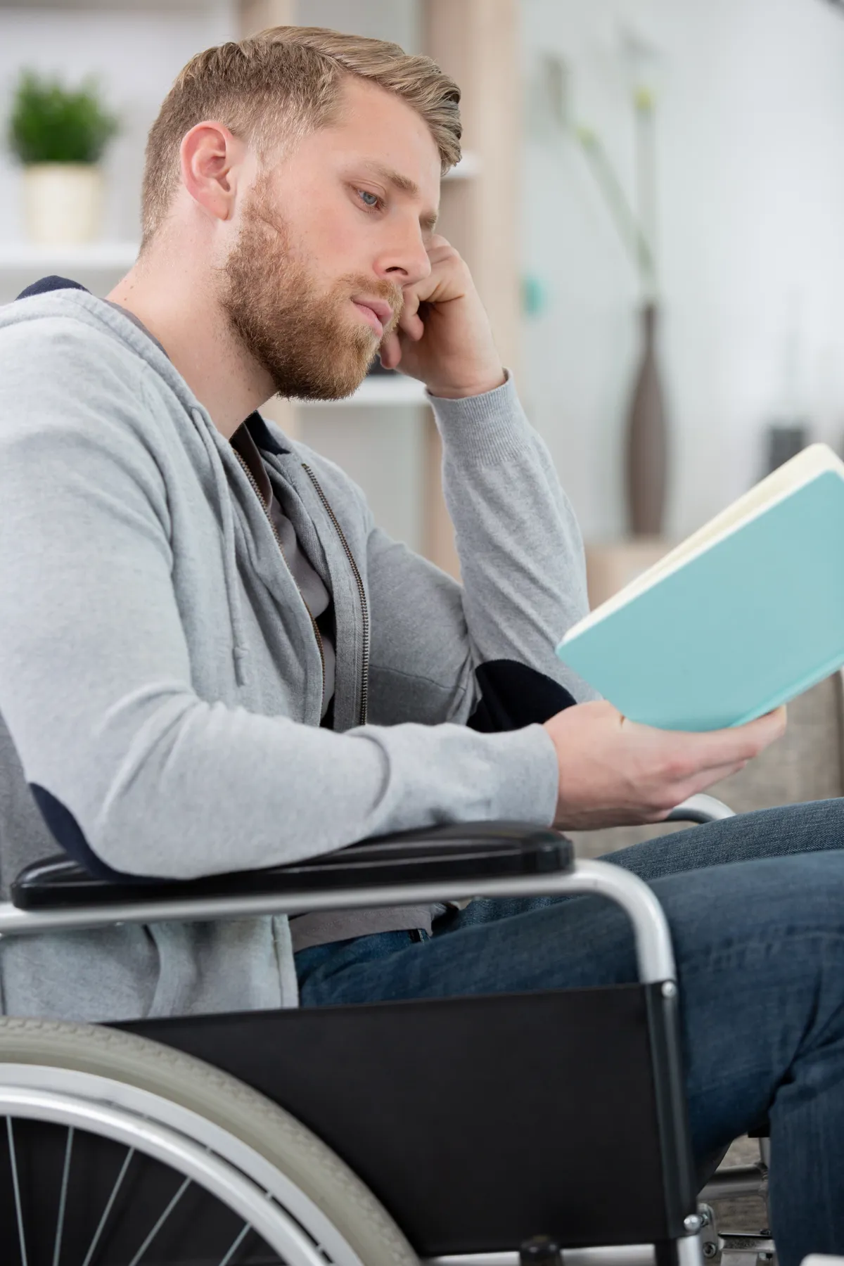 Mand i koerestol laeser i bog