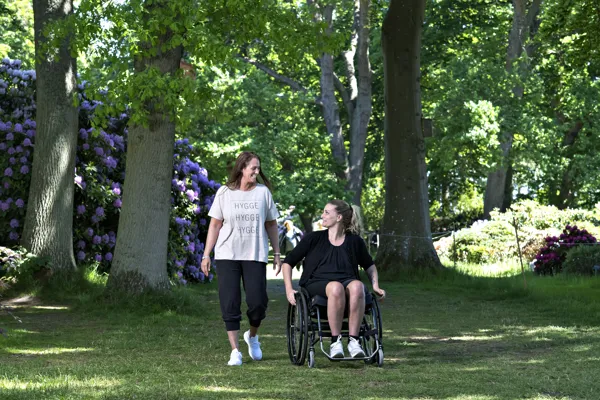 Borger/patient i koerestol er udenfor med en hjælper.