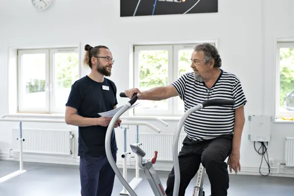 En medarbejder hjaelper patient med at traene i traeningscentret i Roedovre.