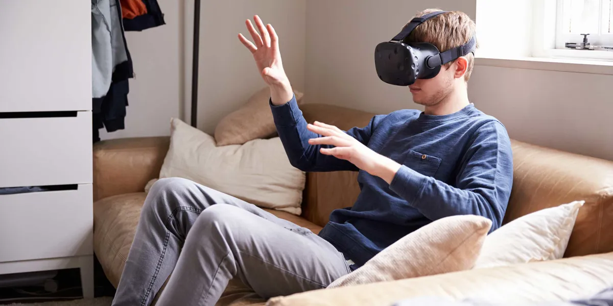 En mand der sidder i en sofa med VR-briller på