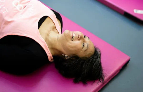 Kvinde ligger smilende på traeningsmaatte